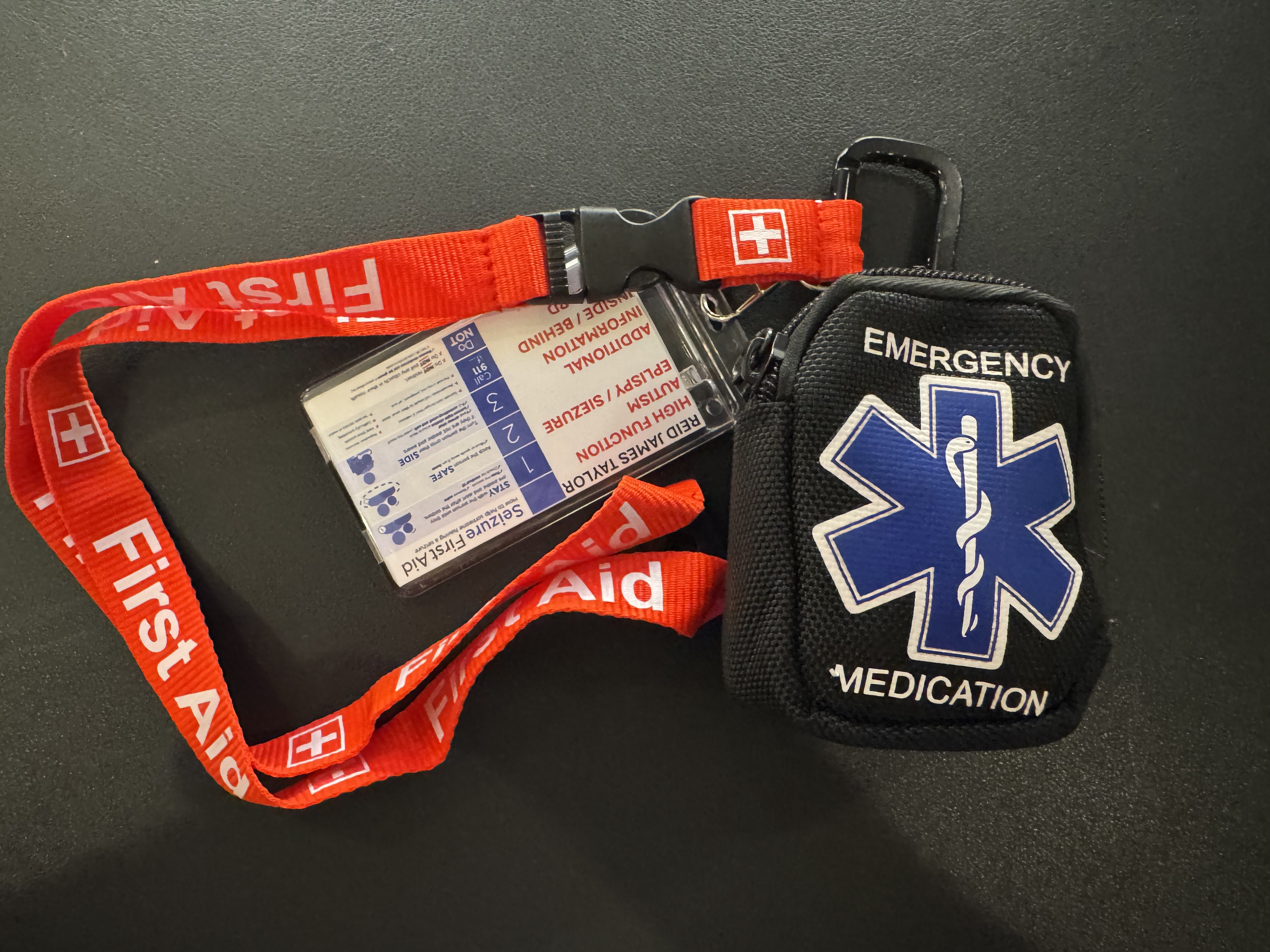 Reid's emergency response kit — a first aid pouch with a seizure information card attached to a red lanyard